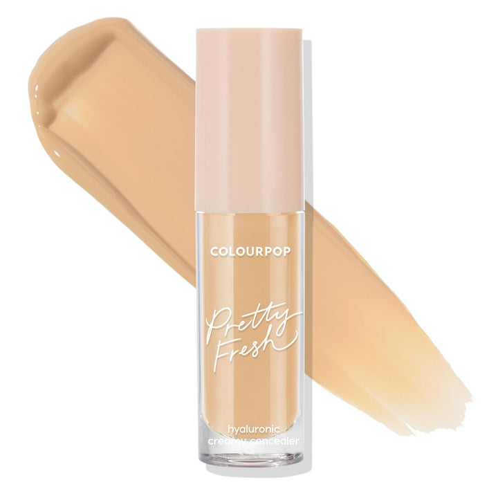 ColourPop Pretty Fresh Creamy Concealer in Medium 90 W stands upright, revealing its hydrating hyaluronic formula; clear tube with blush-pink cap set against two wide warm medium beige swatches on a white background.