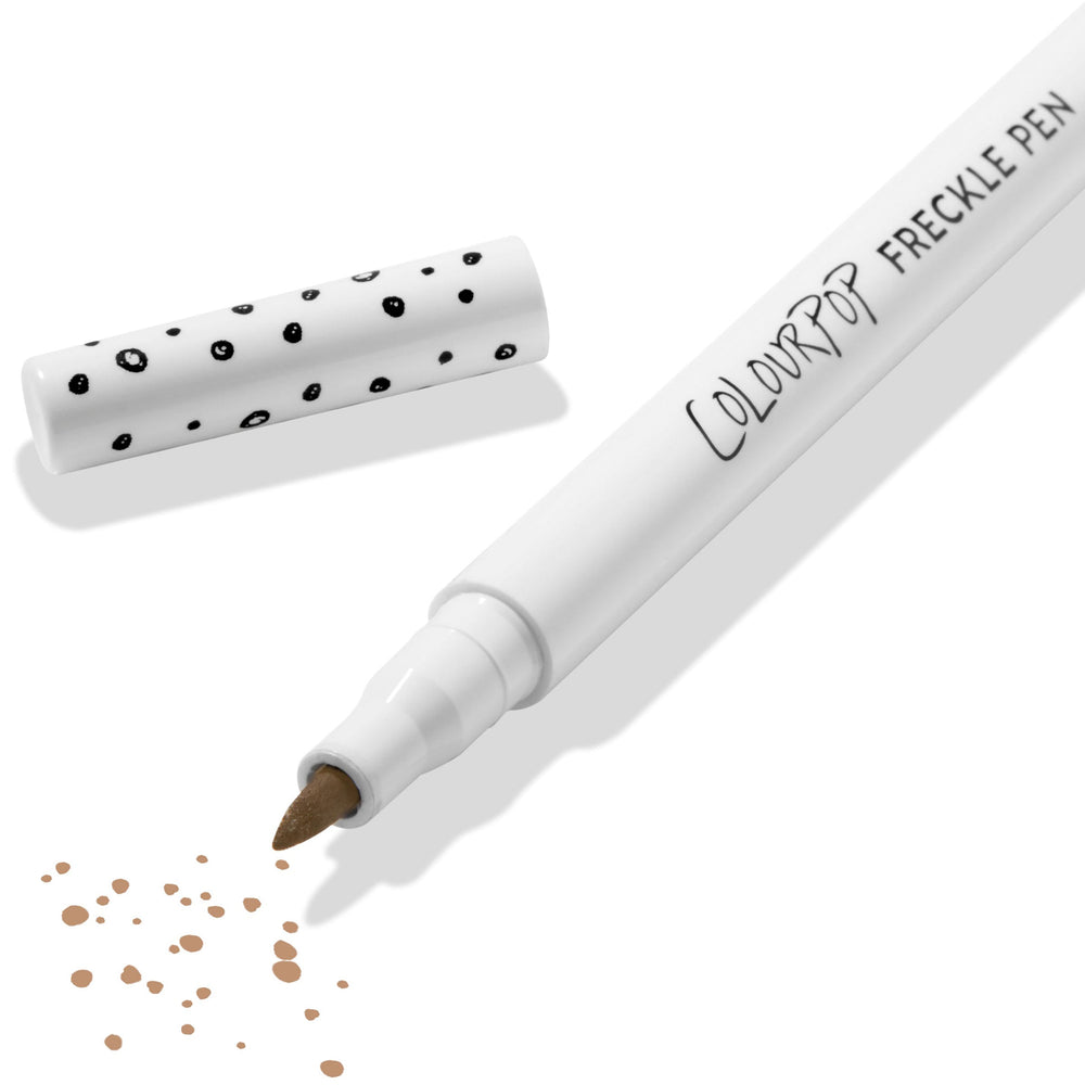 ColourPop Freckle Pen in Soft Brown uncapped, felt-tip applying scattered soft brown freckle dots, with polka-dot white cap beside it on a clean white background; long-wearing, buildable faux freckles makeup.