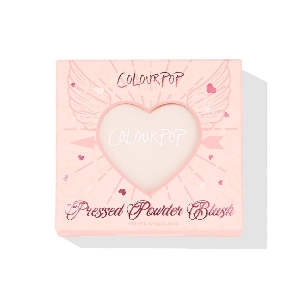 ColourPop Kiss 'N Tell pressed powder blush compact displays through a heart-shaped window in a pink box with winged-heart graphics, front-facing on a white background, 4.45g (0.16 oz) makeup packaging for US shoppers.