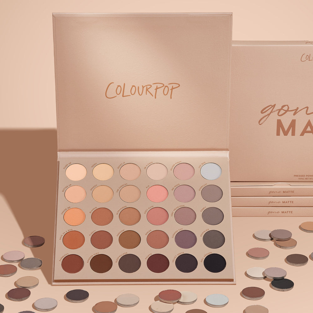 ColourPop Gone Matte shadow palette displaying 30 matte neutral eyeshadows - from ivory and taupe to rose, mauve, terracotta, chocolate, and black - open on a blush-beige backdrop with scattered single pans and stacked boxes.