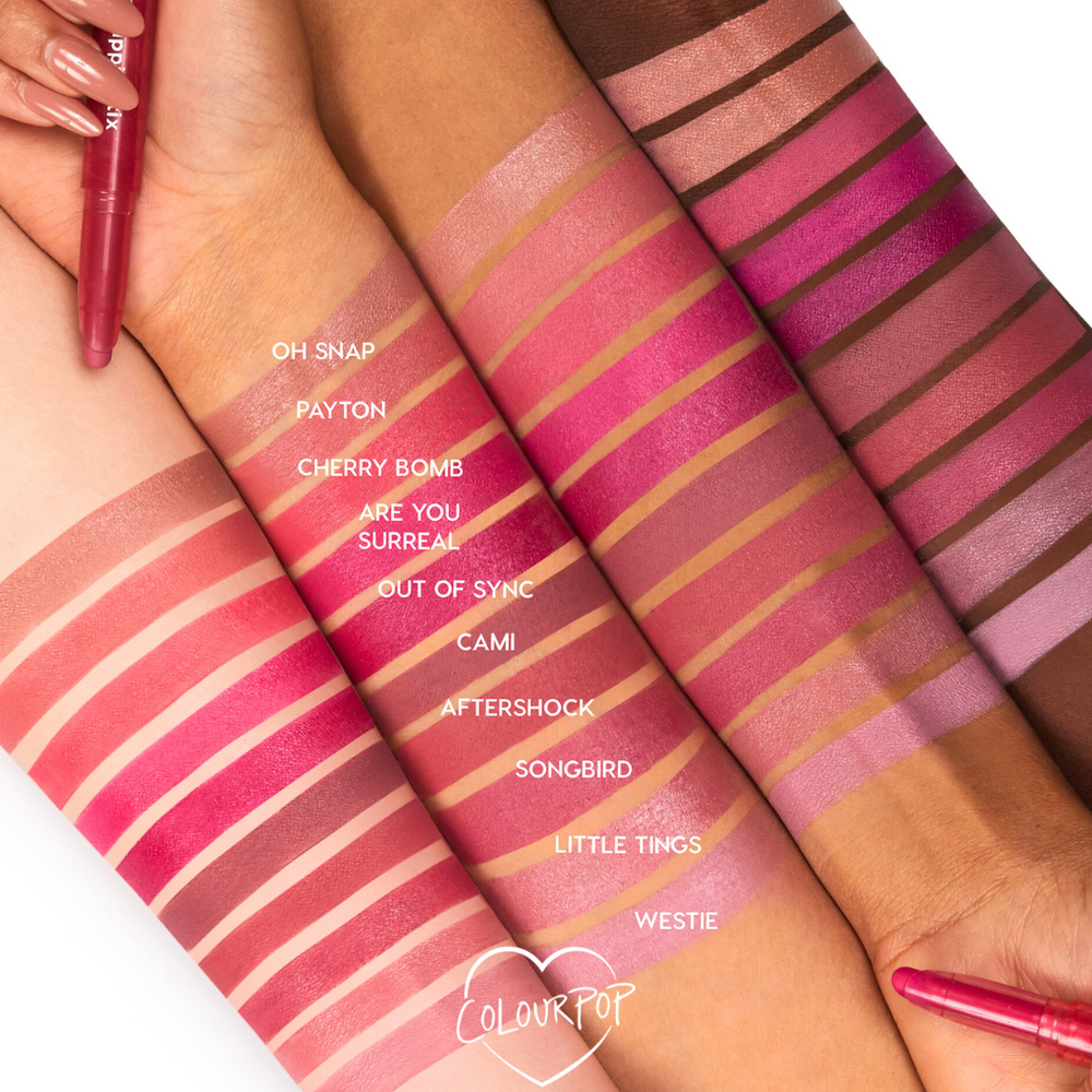 Cami Lippie Stix swatch shown across multiple skin tones, a dusty mauve-pink band among labeled shades (Oh Snap, Payton, Cherry Bomb, Are You Surreal, Out of Sync, Aftershock, Songbird, Little Tings, Westie), with ColourPop Lippie Stix pens framing the forearms.