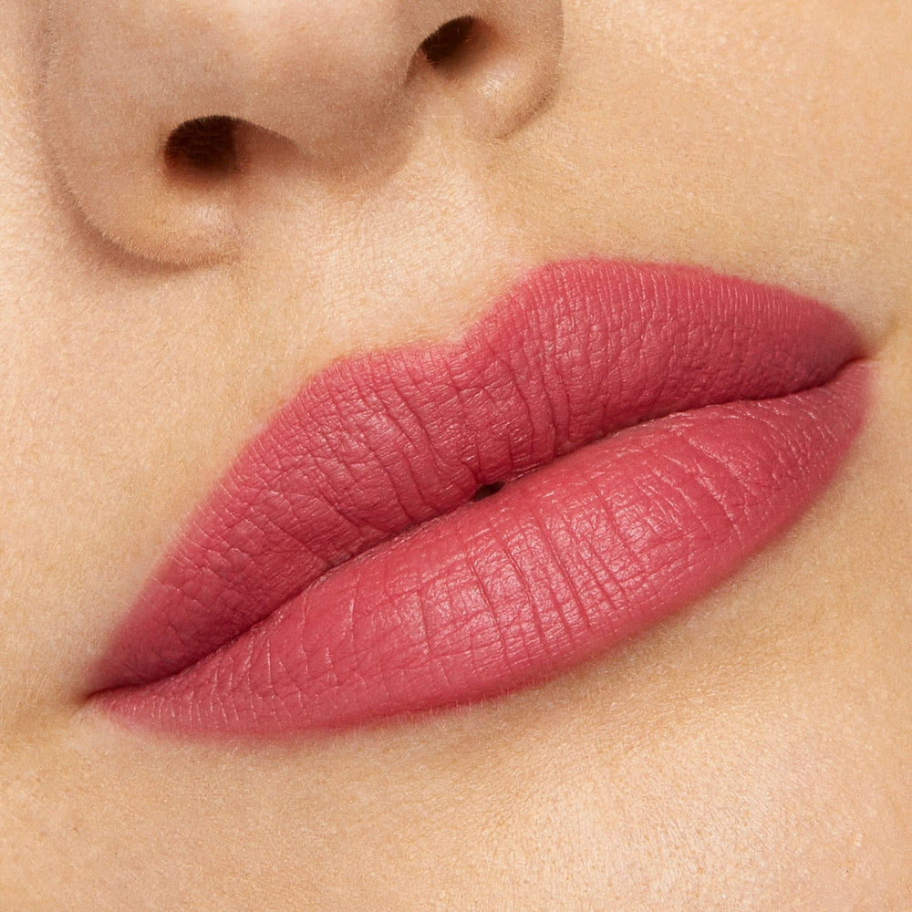 Close-up lips wearing ColourPop Lippie Stix After Shock, a soft-matte rosy pink, showing full, even coverage and creamy texture; swatch shot under bright studio lighting to highlight color payoff and smooth finish.