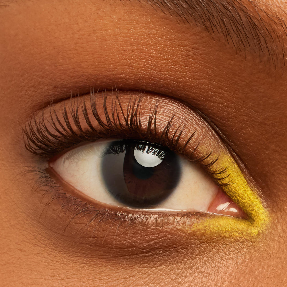 Defined lashes fanning upward, coated in Brownie Points BFF Mascara, on a close-up eye with neutral shimmer shadow and a pop of yellow inner-corner liner, showcasing the rich brown lengthening effect of ColourPop BFF Mascara.