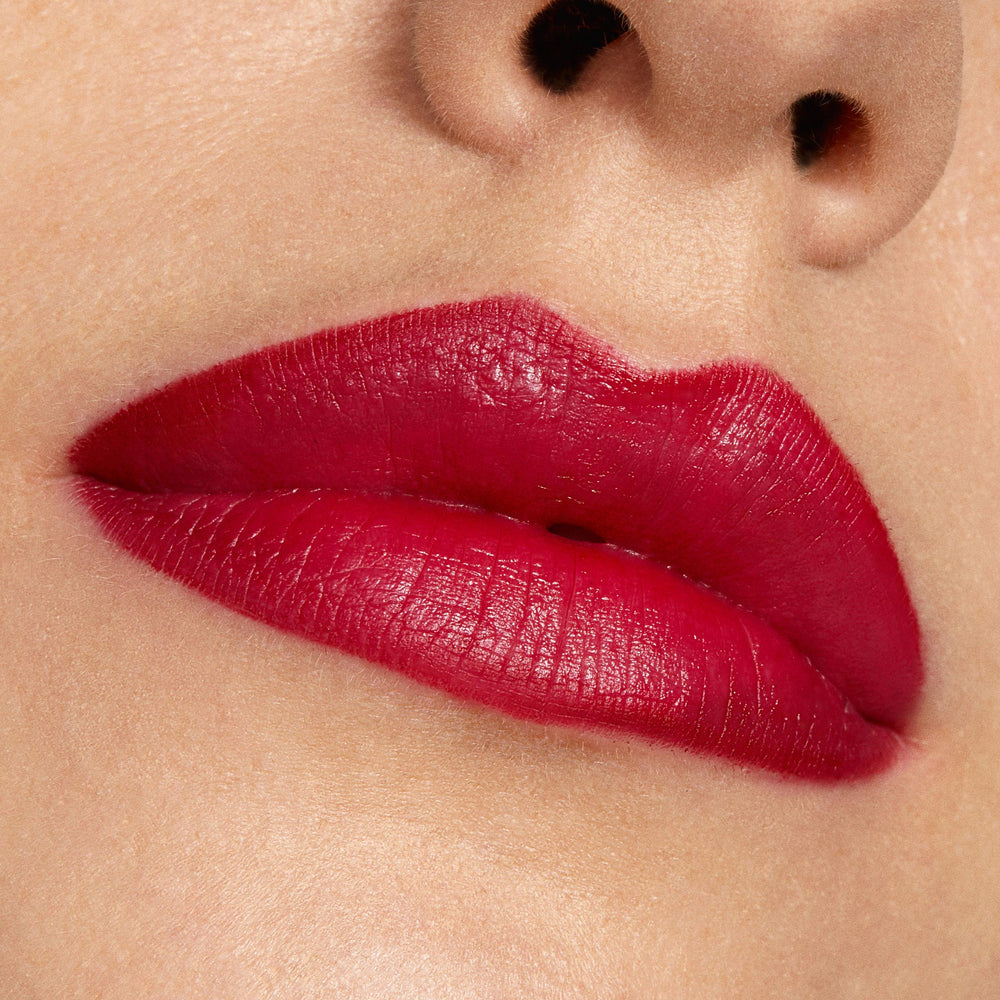 Lips wearing ColourPop Bichette Lippie Stix, showcasing a vivid crimson-red shade with a smooth satin finish and crisp edges, captured in a tight close-up against natural skin to highlight color payoff.