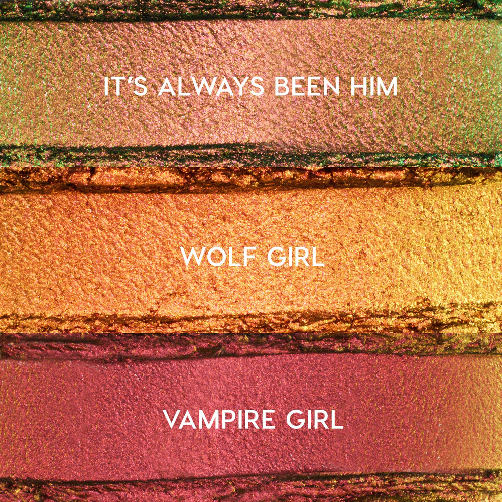 ColourPop Shadow Stix Love Triangle bundle swatches showing three metallic shades - It’s Always Been Him (pink‑green duochrome), Wolf Girl (copper gold), and Vampire Girl (rosy plum) - spread in horizontal strips on a textured makeup surface.