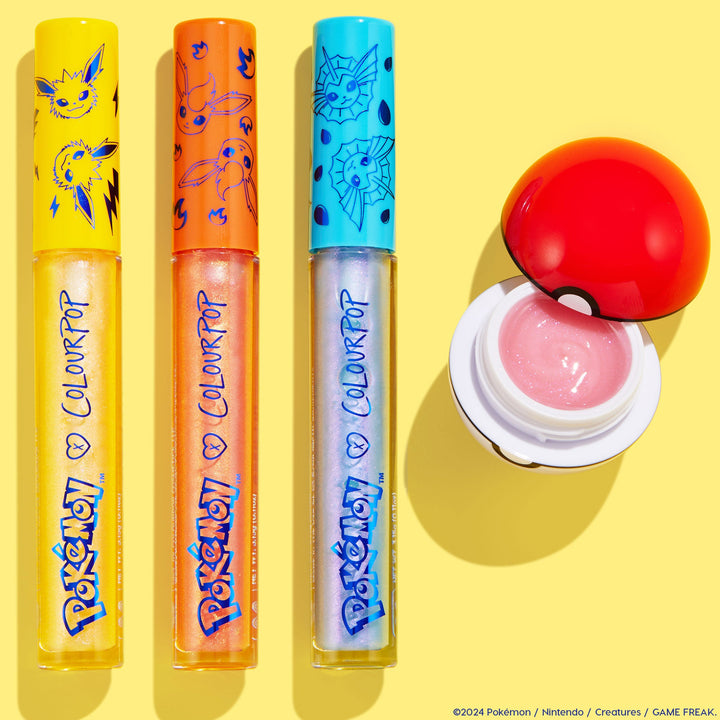 Type Advantage ColourPop Lip Set features three shimmery lip gloss tubes with Pokémon character caps in yellow, orange, and teal plus an open Poké Ball pot of pink balm, arranged in a flatlay on a bright yellow background.
