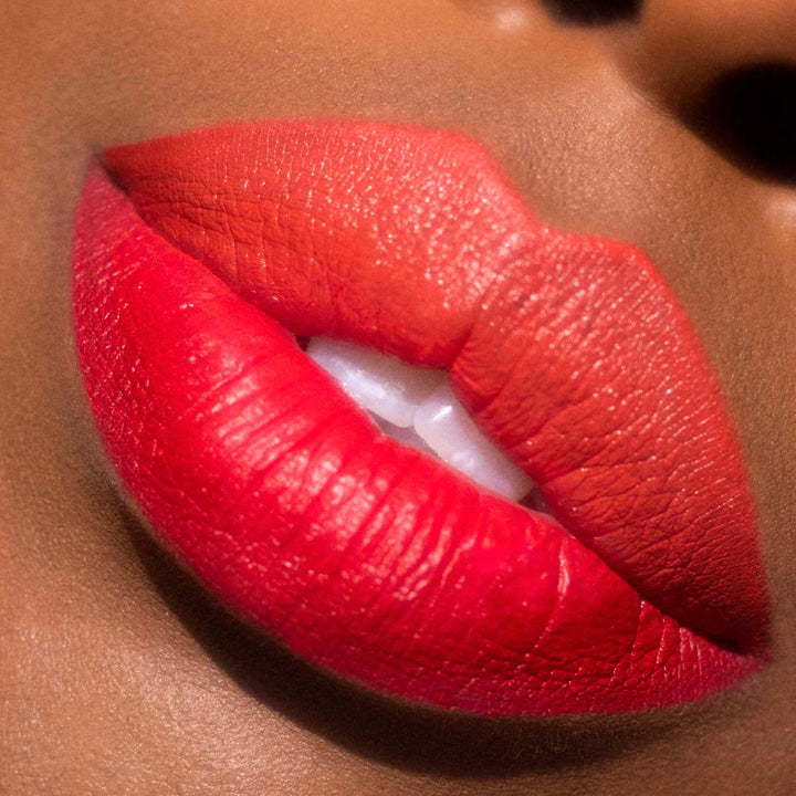 Bold ombré red-to-orange lips lined and filled with ColourPop Bring The Heat Lippie Pencil, lips slightly parted to show teeth, crisp edges and creamy matte payoff in a tight beauty close-up.