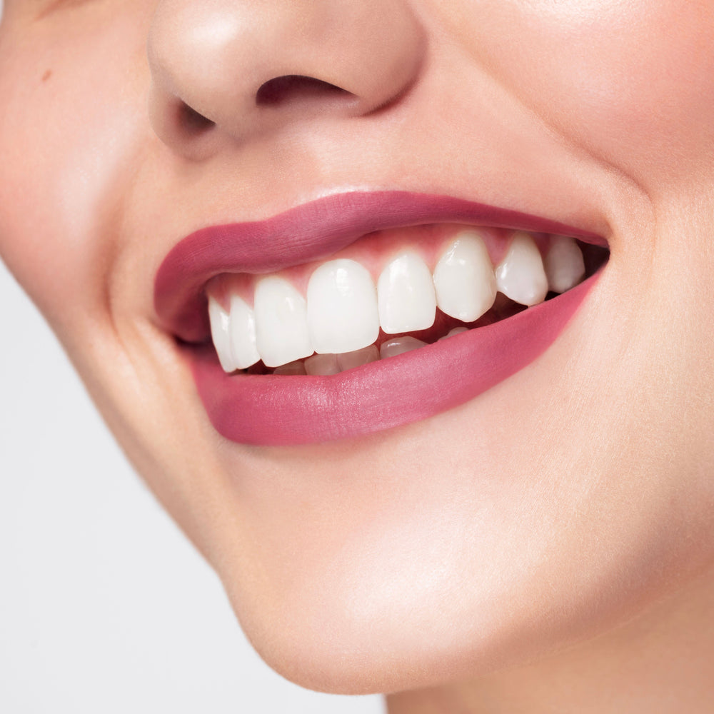 ColourPop Flurries Ultra Matte Lip coats a smiling mouth in cool-toned rosy mauve, showing a smooth, opaque, shine-free finish with clean edges in a tight studio close-up.