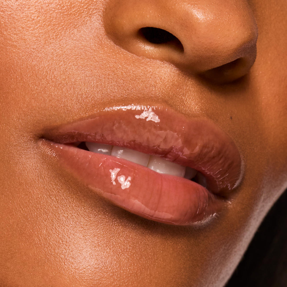 Glossy lips wearing ColourPop Sweet Treats Glossy Lip Balm Trio in a warm cocoa nude, reflecting a high-shine, hydrated finish in a macro close-up against smooth skin.