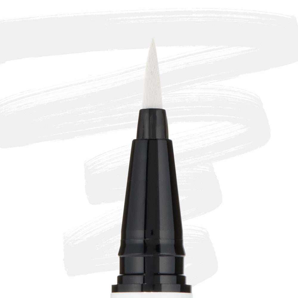 ColourPop BFF Liquid Liner Graceland creating bold white strokes with a fine felt tip; close-up of the black pen barrel and pointed brush, white eyeliner swatches behind, for precise wings and graphic eye looks.