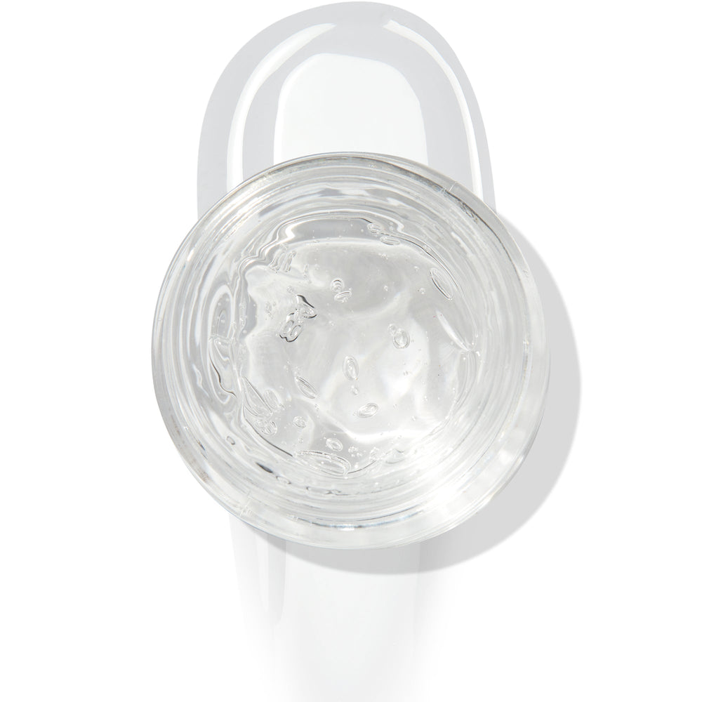 In The Clear Face & Eye Gloss in an open round jar gleams with a glossy swipe beneath it on a white background, showcasing the ColourPop Face & Eye Gloss for dewy, glass-skin shine on lids and cheeks.