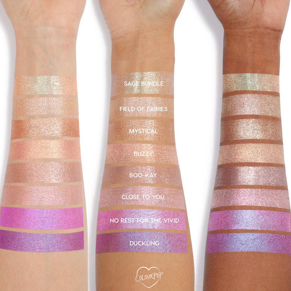 Mystical Jelly Much Shadow by Colourpop swatched on three arms, showing the shimmery peachy-pink eyeshadow stripe labeled Mystical alongside other metallic pastel shades for a multi-skin-tone comparison of Colourpop eyeshadow payoff.