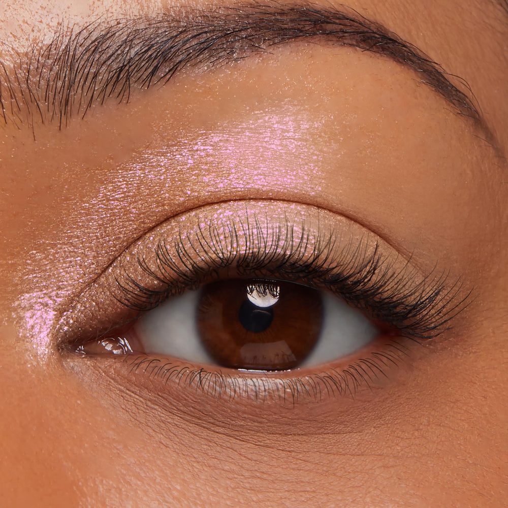 Shimmering pink-lilac duochrome eyeshadow worn on a brown eye in a macro close-up, showcasing the iridescent payoff of ColourPop Jelly Much Shadow in Field of Fairies, a gel-cream that gleams across the lid and inner corner with metallic sheen.