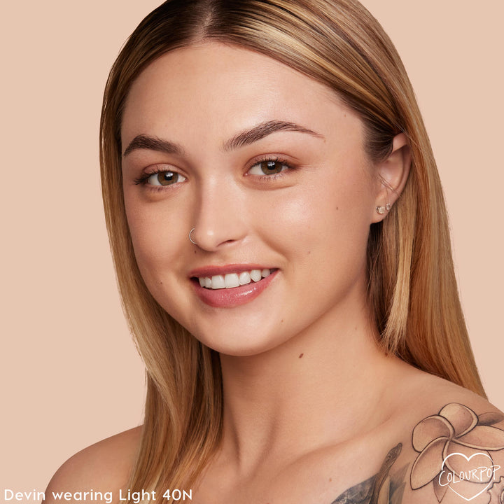 ColourPop Pretty Fresh Creamy Concealer in Light 40 N shown on a model, brightening under-eyes and evening tone with natural, dewy medium coverage; close-up studio shot against a peach backdrop highlights the light neutral shade match.