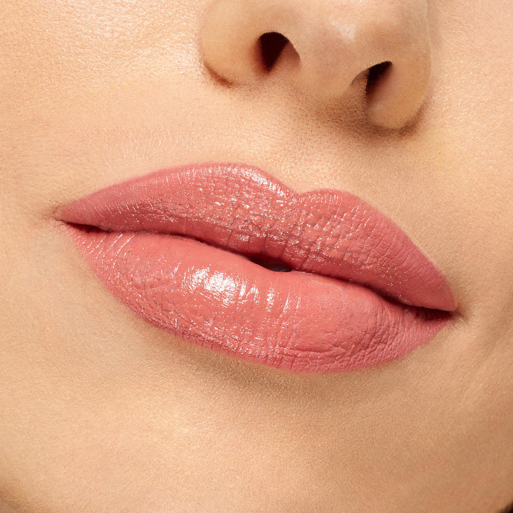 Lips wearing NBD ColourPop Lippie Stix, a warm nude-pink with a creamy, glossy finish, shown in an extreme close-up under studio lighting to display smooth, even coverage and natural shine.