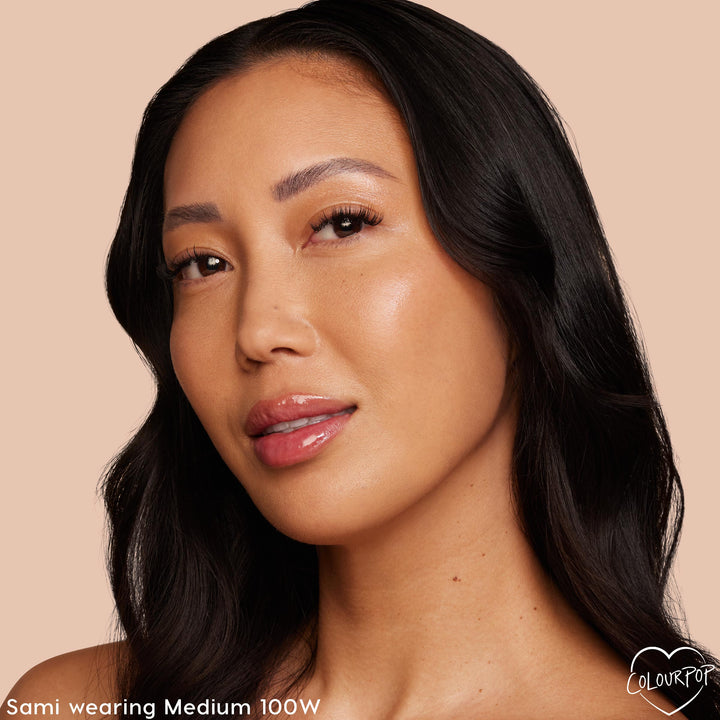 ColourPop Hyaluronic Hydrating Foundation in Medium 100 W delivering dewy, even medium coverage on a model’s face, showcasing smooth skin and a natural glow in a studio close-up against a soft beige background.
