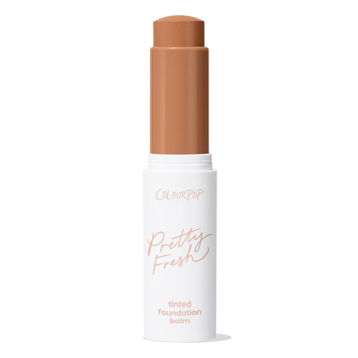 ColourPop Pretty Fresh Tinted Foundation Balm in Dark 18 - twist-up stick stands open with the warm deep shade bullet extended, housed in a white tube with peach lettering against a clean white background.