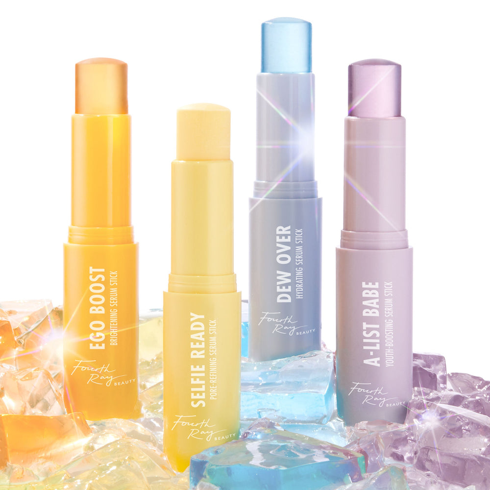 Ego Boost brightening ColourPop Serum Stick by Fourth Ray Beauty stands uncapped in an orange twist-up tube, balm exposed, grouped with Selfie Ready, Dew Over, and A‑List Babe sticks atop iridescent gel cubes in a glossy studio flatlay.