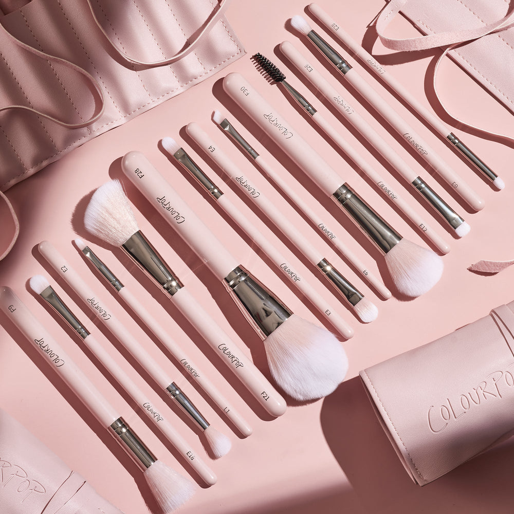 Smoke 'N Roses Brush Roll displaying a full ColourPop Makeup Brush Kit: pink-handled powder, blush, eyeshadow, angled liner, and spoolie brushes with silver ferrules, arranged in a flat lay beside a blush-pink roll-up case embossed ColourPop.