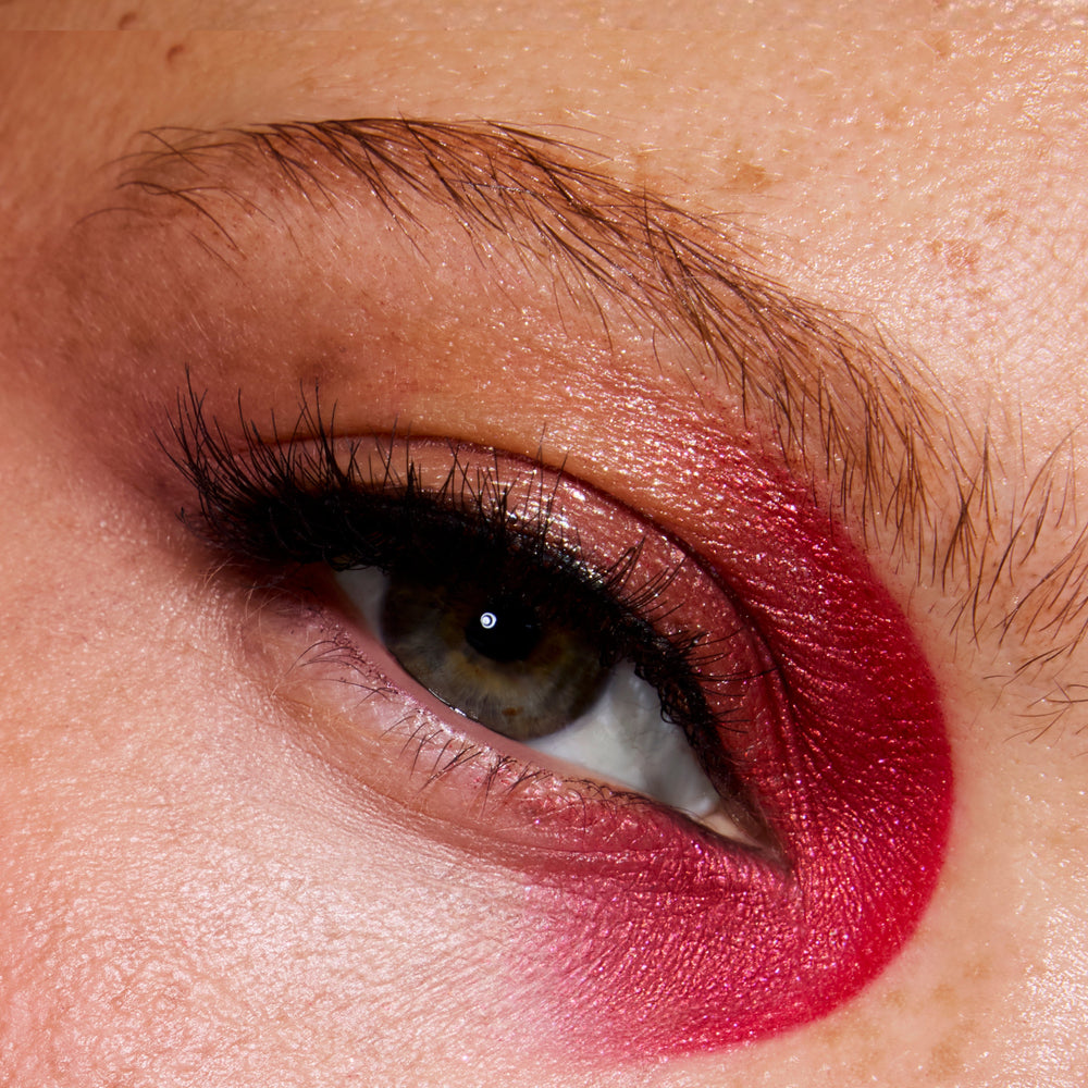 Close-up of a model’s eye wearing ColourPop Eternal Eclipse eye trio, featuring bold Twilight-inspired red and berry shadow wrapped under and around the eyelid with shimmering rose tones and defined lashes on natural, freckled skin.
