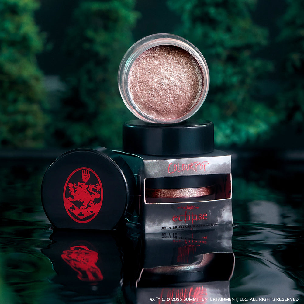 ColourPop Cullen Coven Jelly Much Shadow, a shimmery rose-bronze cream eyeshadow from the Twilight collection, opened and stacked on its Eclipse packaging against a dark, misty forest backdrop with reflections on glossy black water.