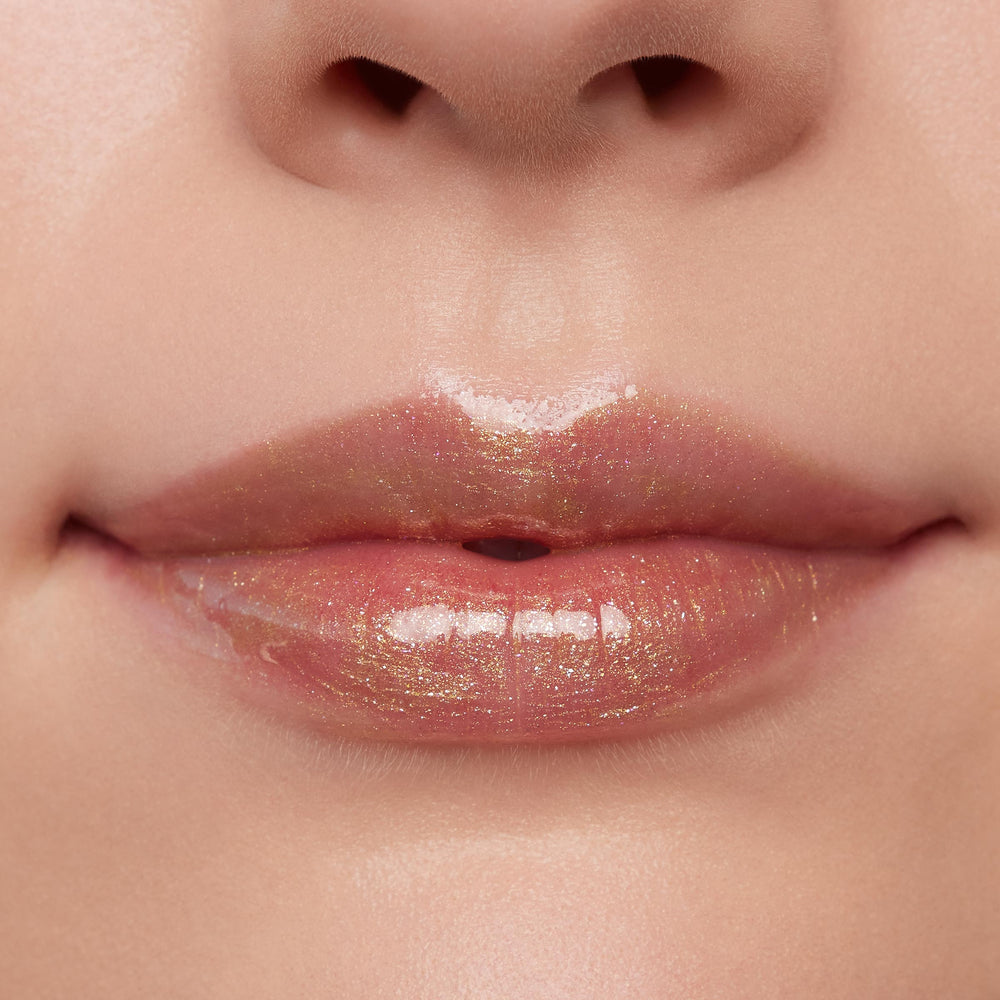 Glossed lips wearing ColourPop Ultra Glossy Lip in Pascal, a sheer clear gloss with gold micro-shimmer, reflecting studio light for a high-shine finish in a close-up beauty swatch.