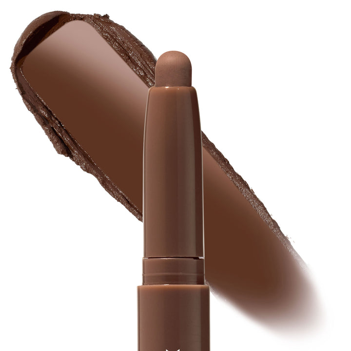 ColourPop Shadow Stix in Walnut Ave stands uncapped, showing a rounded tip while a broad swatch behind reveals a rich warm walnut-brown pigment; creamy, blendable eyeshadow stick on a clean white background.