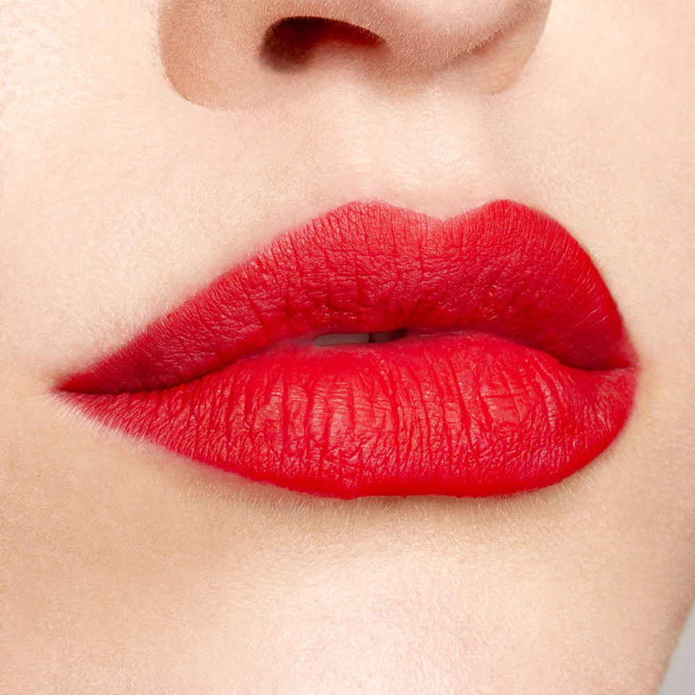 Bold red lips wear Bossy, a ColourPop Lippie Pencil, lining and filling the mouth with rich matte true red; crisp edges and full coverage shown in a close-up beauty shot against natural skin.